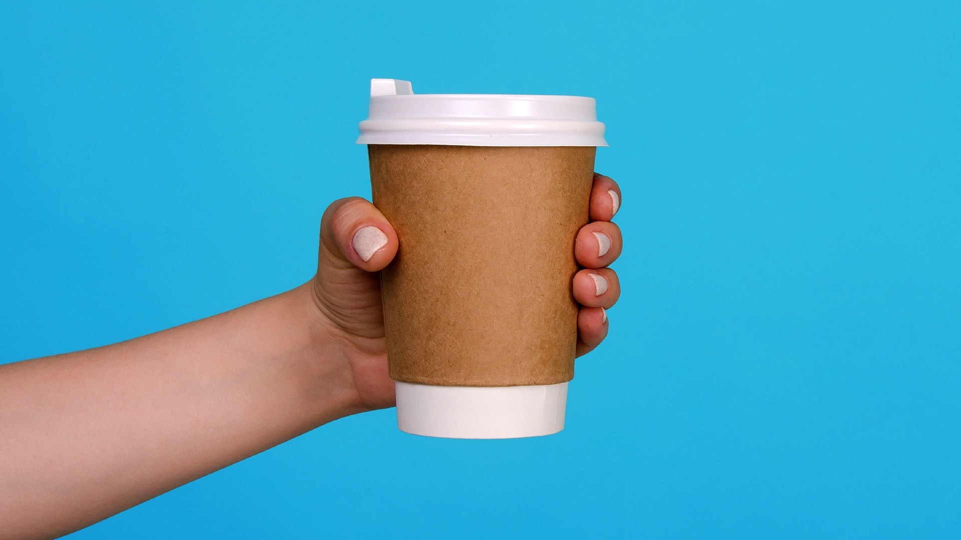 A photograph of a hand holding a takeaway coffee cup with a blue, solid coloured background for a NEO insights article