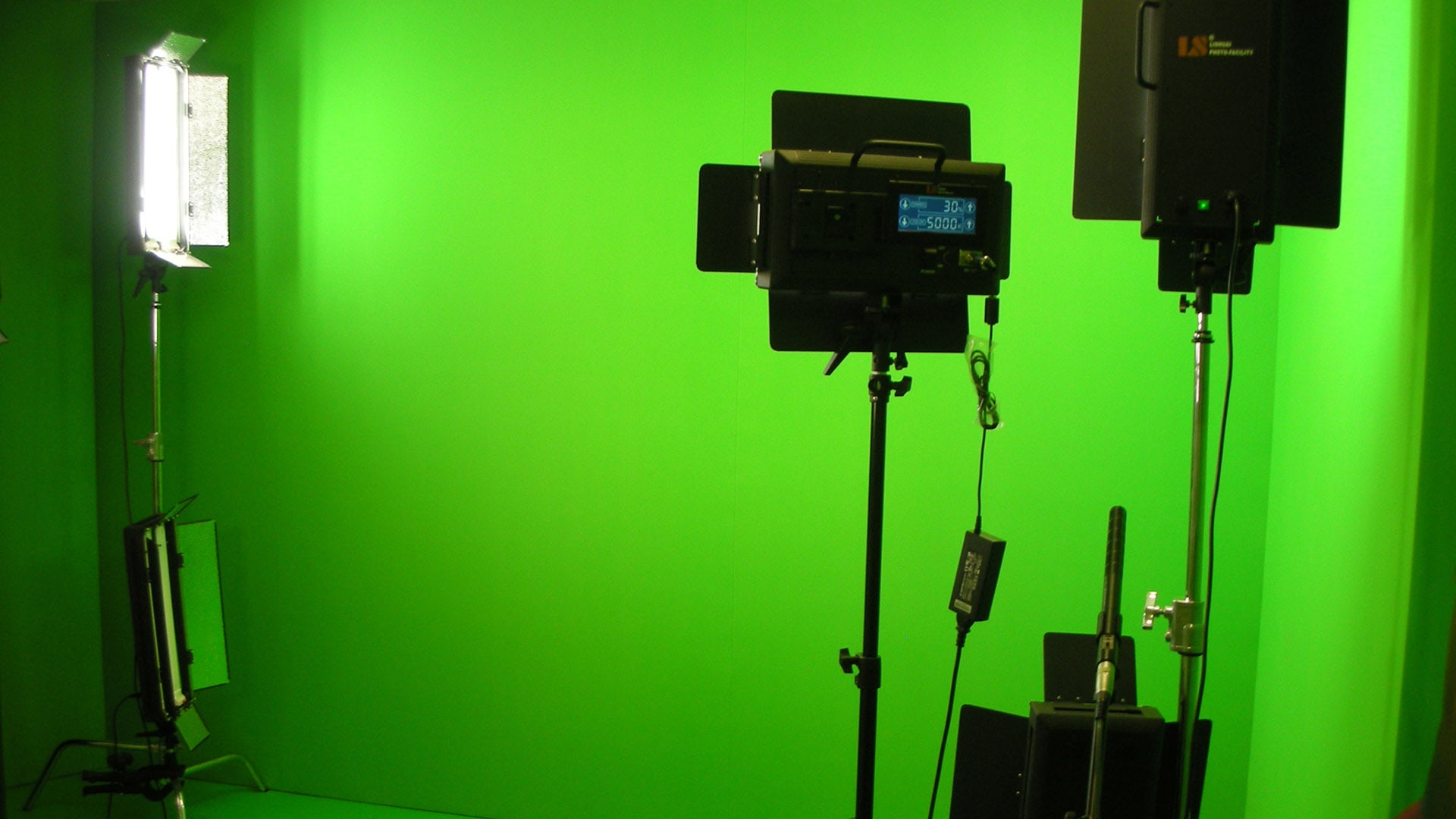 A photograph of greenroom lighting for a client with lights and photography equipment with green walls.