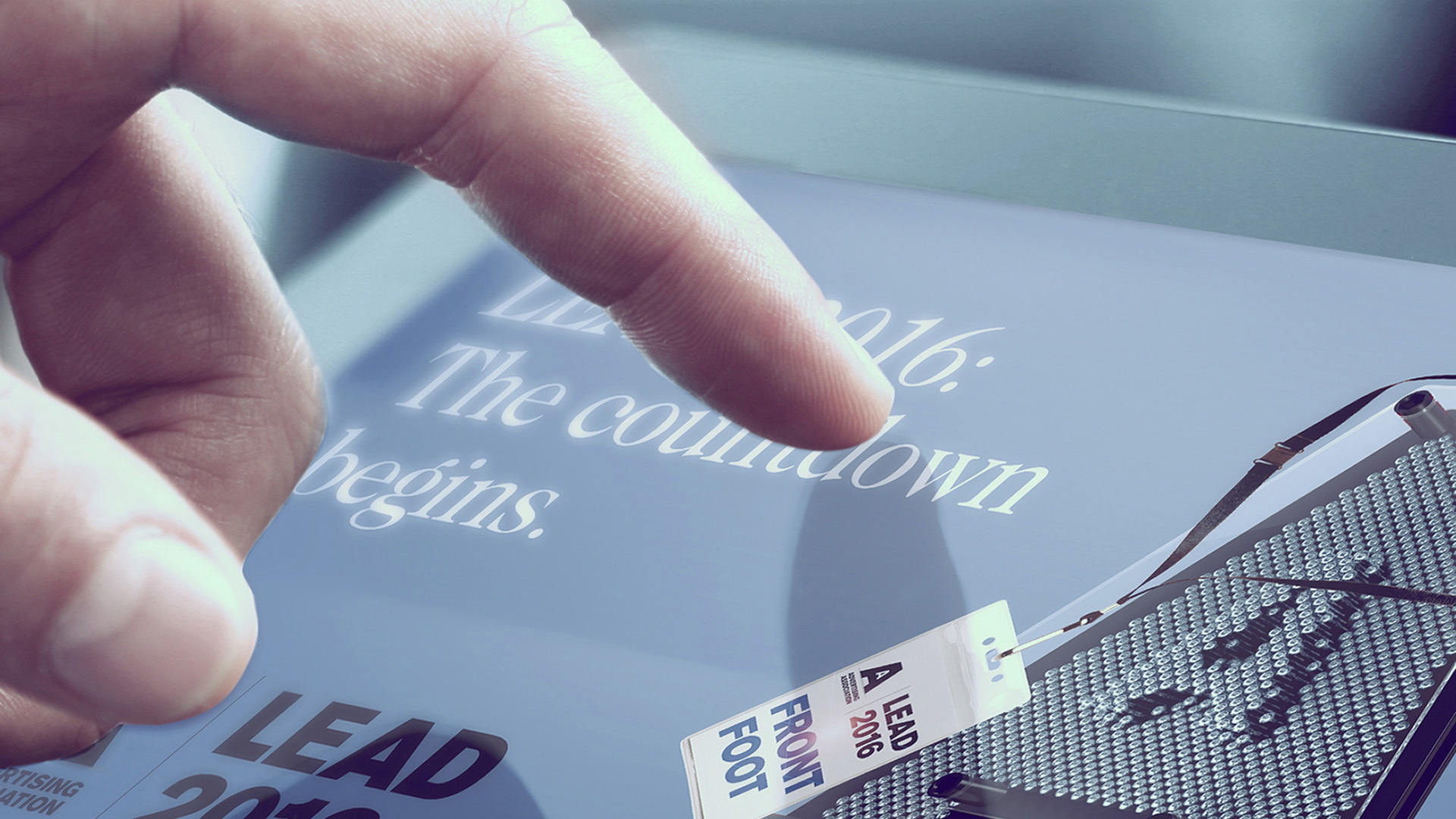A person's fingers touching the screen of an electronic tablet displaying the Advertising Association LEAD Conference Advert