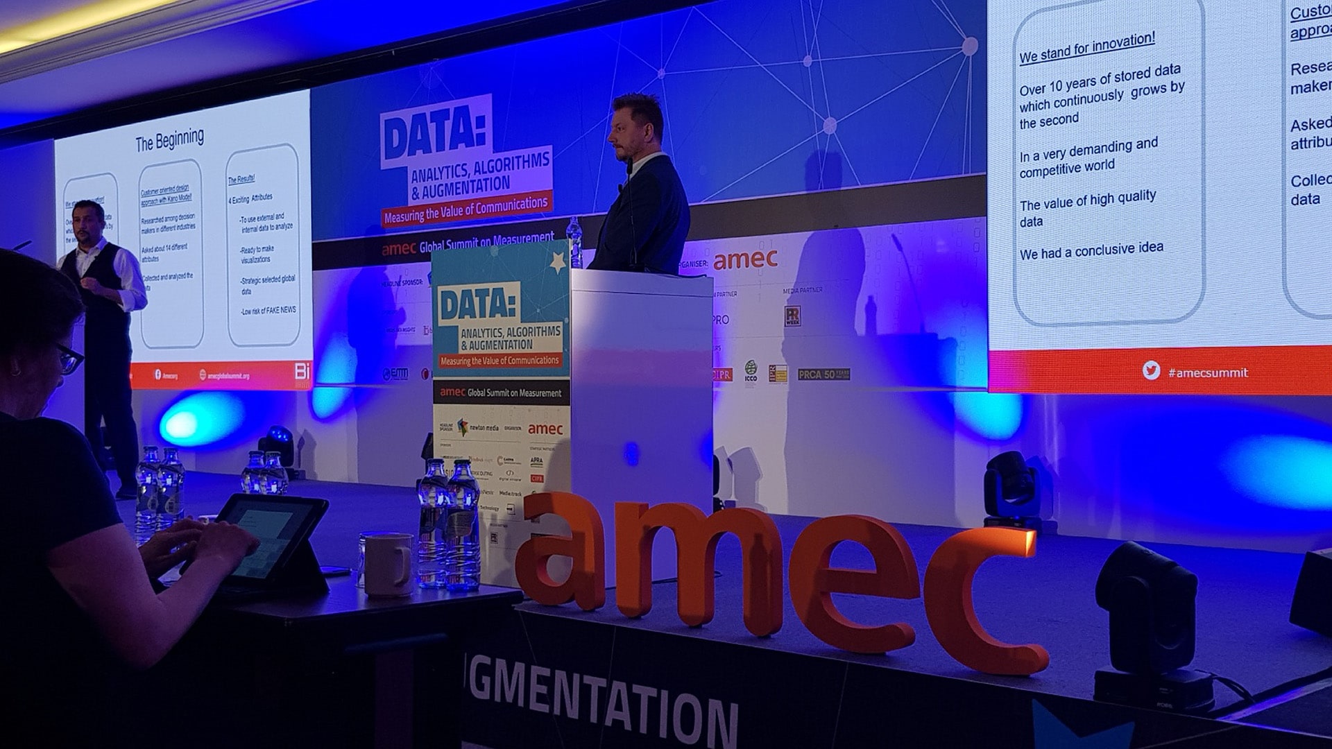 A photograph of a speaker at an indoor event for the AMEC awards 2019