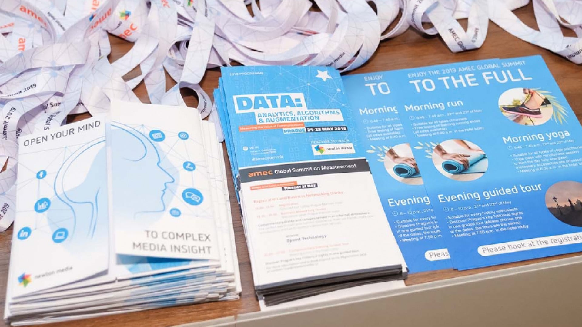 A photo of a stack of flyers and brochures for the Association for the Measurement and Evaluation of Communication AMEC Global Summit Programme