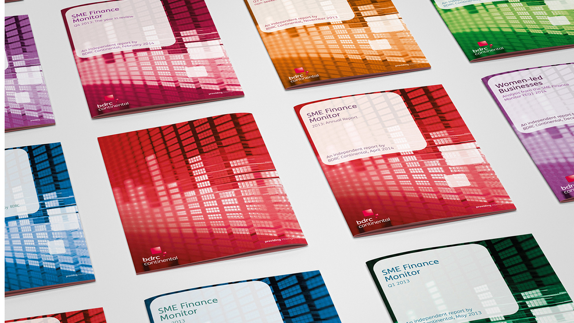 A selection of colourful BVA BDRC SME Finance Monitor Report Covers on a grey surface