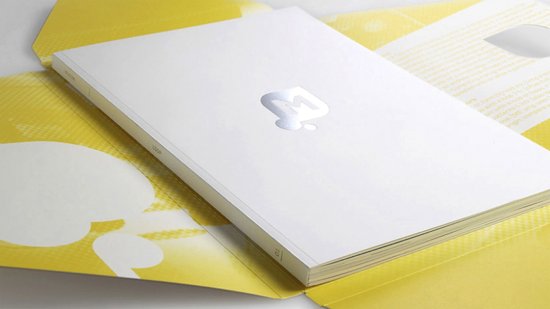 A Mintel Loop white book cover with silver logo and yellow outer packaging on a white surface